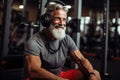 Man Wearing Headphones Sitting in Gym, Fitness Enthusiast Focuses on Music During Workout, happy smiling retired sportsman in