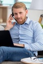man wearing headset and using laptop sat on sofa Royalty Free Stock Photo
