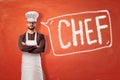 Man wearing kitchen apron and chef hat with a sign on red background Royalty Free Stock Photo