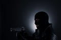 Man wearing knitted balaclava with gun on black Royalty Free Stock Photo