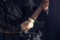 A man wearing a leather jacket playing a black and yellow electric guitar with black background Royalty Free Stock Photo