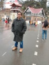 A man wearing long coat standing in open road with presence of lots of people Royalty Free Stock Photo