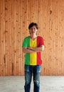 Man wearing Mali flag color shirt and cross one`s arm on wooden wall background Royalty Free Stock Photo