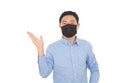 A man wearing a mask makes an explanatory gesture in front of a white background