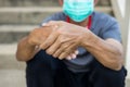 A man wearing a mask sits on the stairs squeezing his hands