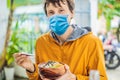 Man wearing a medical mask during COVID-19 coronavirus eating Raw Organic Poke Bowl with Rice and Veggies close-up on Royalty Free Stock Photo