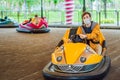 Man wearing a medical mask during COVID-19 coronavirus having a ride in the bumper car at the amusement park