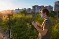 A man wearing a medical mask records a video blog on how to protect himself from the virus at sunset in a park Royalty Free Stock Photo