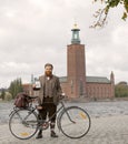 Man wearing old fashioned tweed suit and hat holding a retro bicycle in front of Stockholm City Hall Royalty Free Stock Photo