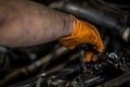 A man wearing an orange glove fixing and doing maintenace on a car engine in an auto repair shop Royalty Free Stock Photo