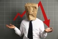 Man wearing paper bag with drawn sad face and illustration of falling down chart on light grey background. Economy recession Royalty Free Stock Photo