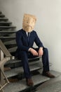 Man wearing paper bag with drawn sad face indoors Royalty Free Stock Photo