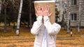 Man wearing paper bag with happy emotion, man in mask standing outdoor and overing his face with his two hands.