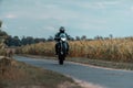 Man wearing a protective helmet on a black motorcycle traveling down a winding road