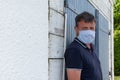 Man wearing protective mask against transmissible infectious diseases coronavirus against wooden wall outdoors Royalty Free Stock Photo