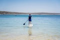 Man wearing rash guard on a stand-up paddle board at the ocean bay in Australia. SUP water sport activity Royalty Free Stock Photo