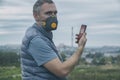 Man wearing a real anti-smog face mask and checking current air pollution with smart phone app