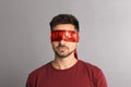 Man wearing red blindfold with word Atheism on light grey background