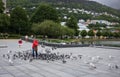 A man wearing a red coat feeds birds