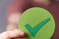 Man wearing a red shirt and holding a green sign with a tick Royalty Free Stock Photo