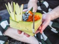 Man wearing a sarong holding a Balinese offering