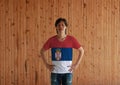 Man wearing Serbia flag color shirt and standing with akimbo on the wooden wall background. A horizontal tricolor of red blue and Royalty Free Stock Photo