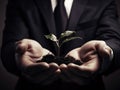 A man wearing a suit is holding a small sapling in his hands