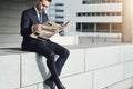 Man wearing suit sitting and reading newspaper