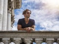 Photo of a stylish man leaning on a balcony railing wearing sunglasses