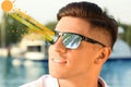 Man wearing sunglasses outdoors, closeup. UVA and UVB rays reflected by lenses, illustration