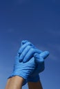 Man wearing surgical gloves clasping his hands