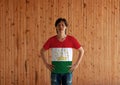 Man wearing Tajikistan flag color shirt and standing with akimbo on the wooden wall background