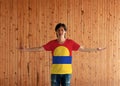 Man wearing United States Minor Outlying Islands flag color shirt and standing with arms wide open on the wooden wall background