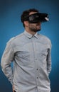 Man wearing virtual reality goggles. Studio shot, blue backgrou