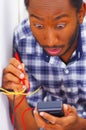 Man wearing white and blue shirt working on electrical wall socket wires using multimeter, electrician concept
