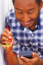 Man wearing white and blue shirt working on electrical wall socket wires using multimeter, electrician concept