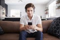 Man Wearing Wireless Headphones Sitting On Sofa At Home Streaming From Mobile Phone Royalty Free Stock Photo