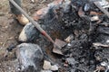 Man in workboots cleaning out fire pit with shovel