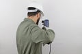 Man wearing worker uniform and hardhat holding drill tool standing backwards Royalty Free Stock Photo