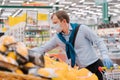 Man wears disposable medical mask and gloves in big supermarket, makes shopping, chooses necessary food products, protects himself