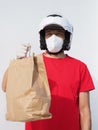 The man wears a kn95 mask and motorcycle helmet, delivers a paper cardboard bag.