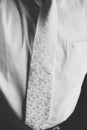 Man wears a white tie with a silver fowers over a white shirt