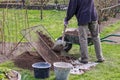 Man wears work outfit. Gardener prepare earth for new flowers and trees. He sifting soil through handmade sieve for better