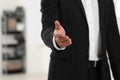 Man welcoming and offering handshake indoors, closeup. Space for text