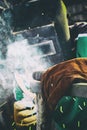 A man in weld mask with electric weld in his hand welding a metal frame