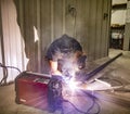 A man welds two pieces of metal together with an arc welder in a shop Royalty Free Stock Photo