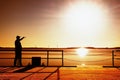 Man on wharf construction and photograph morning sea. Tourist with smart phone above smooth water