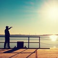 Man on wharf construction and photograph morning sea. Tourist with smart phone above smooth water