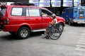 Man in wheel chair guides a vehicle out of a parking slot at a public parking area