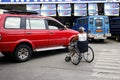 Man in wheel chair guides a vehicle out of a parking slot at a public parking area
